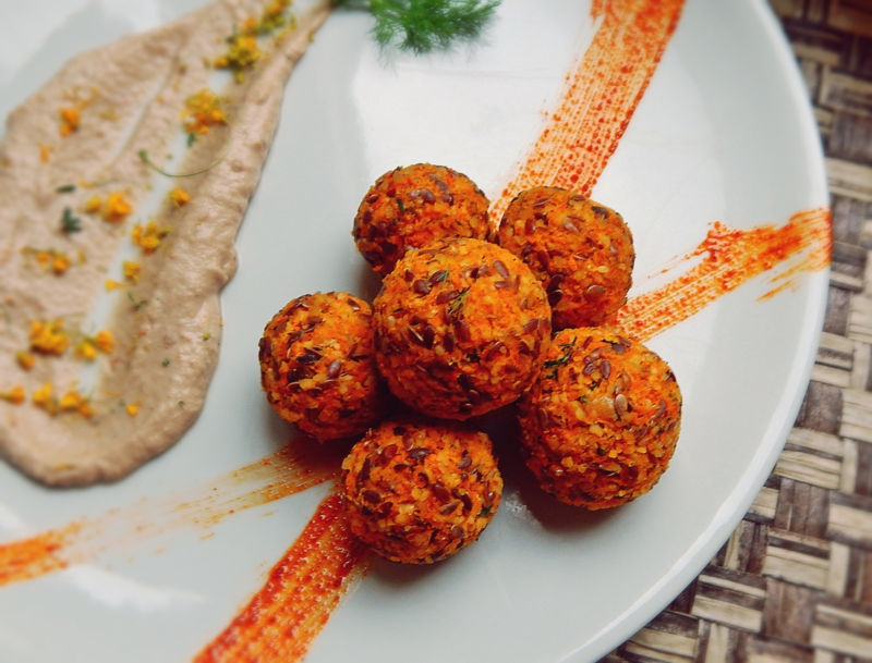 Polpettine crudiste disposte a stella su un piatto bianco, al di sotto due strisce di salsa arancione, accanto una cucchiaiata spalmata di salsa