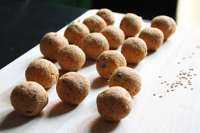 Su un tagliere di legno alcuni falafel crudisti in preparazione