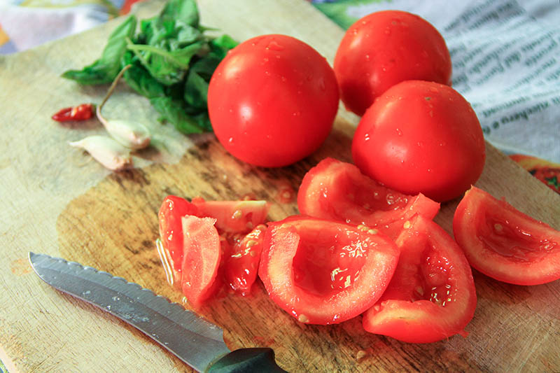 Su un tagliere: Pomodori, basilico, aglio e peperoncino