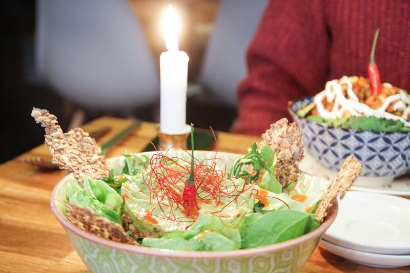 bowl con insalata, cracker, germogli su un tavolo illuminato da candela