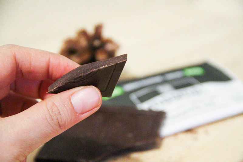 Un pezzetto di tavoletta di cioccolato tenuto tra due dita